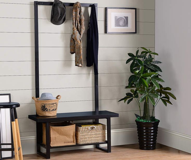 an entryway with a bench, coat rack and potted plant