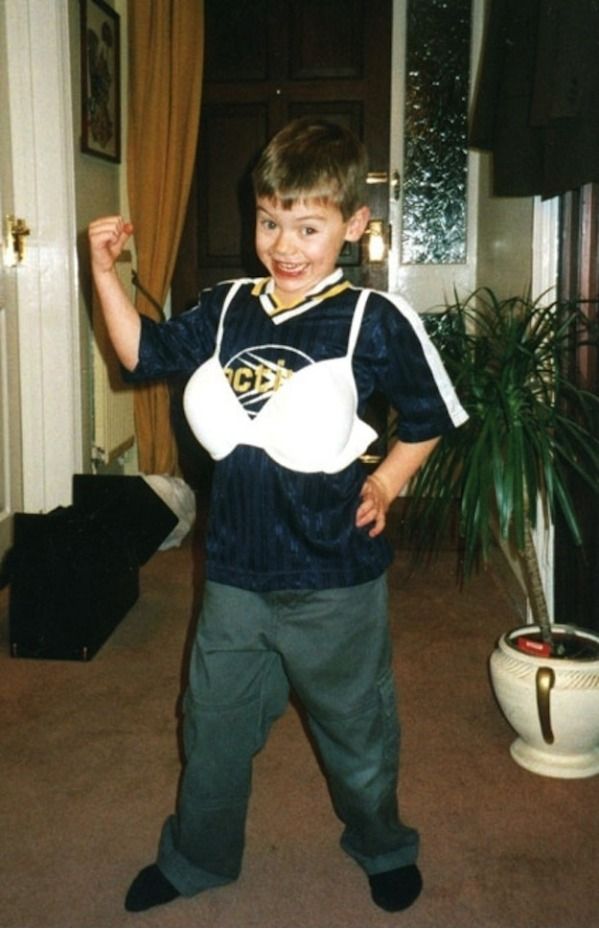 a young boy standing in front of a doorway with his fist up and smiling at the camera