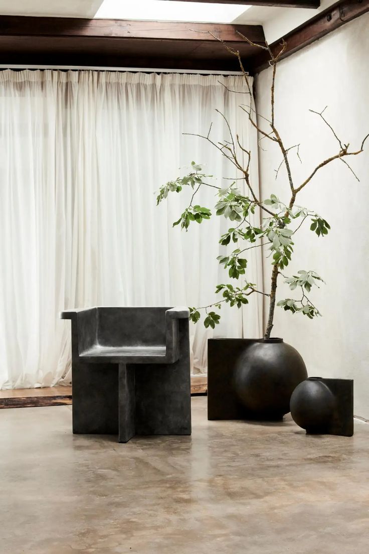 two black vases and a bench in front of a curtained window