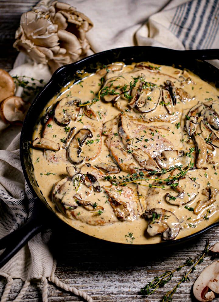 a skillet filled with mushroom gravy on top of a table next to mushrooms