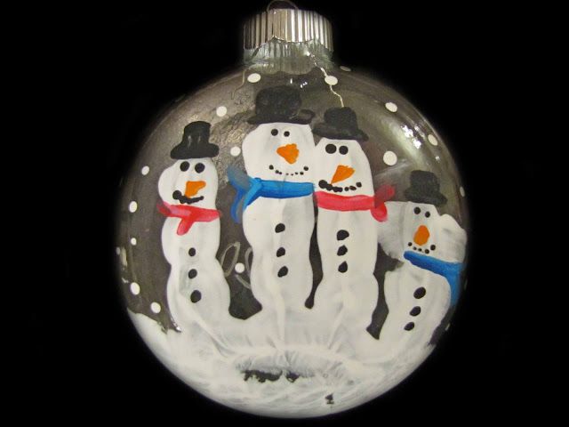 a glass ornament with three snowmen on it