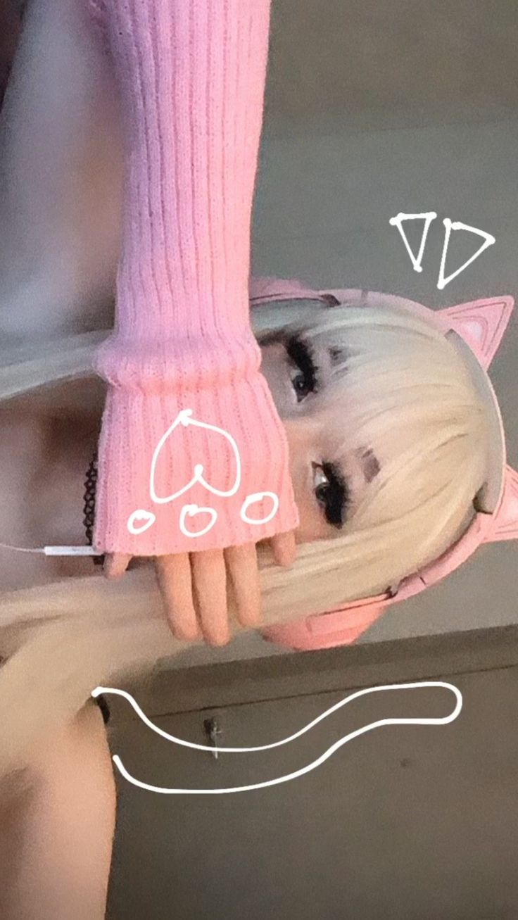 a doll with white hair wearing a pink outfit and holding onto a cat headband