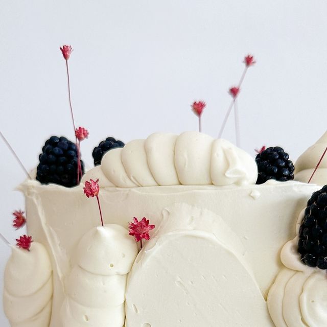 a cake with white frosting and blackberries on top