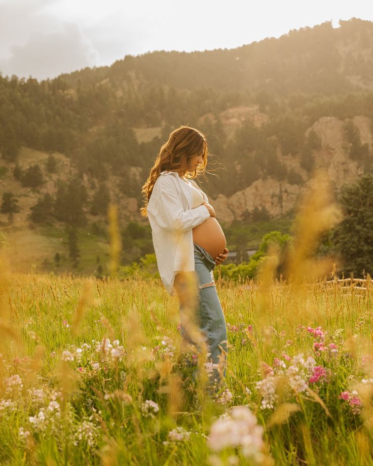 a pregnant woman standing in the middle of a field