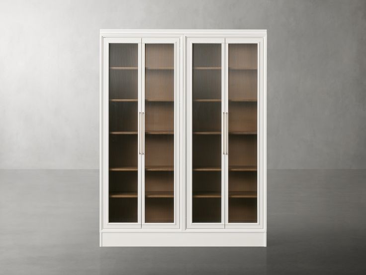 a white bookcase with glass doors on the front and side, in an empty room