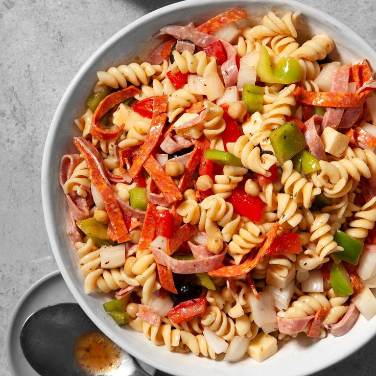 a white bowl filled with pasta salad on top of a table