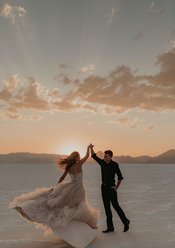 a couple dancing in the desert at sunset