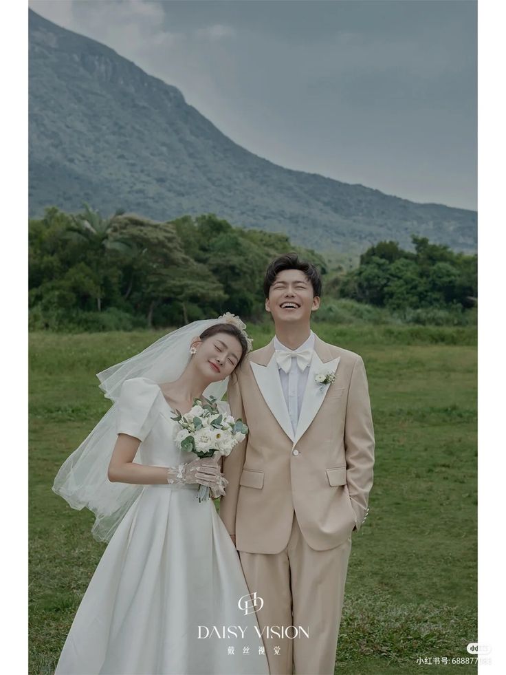 a man and woman standing next to each other in front of a lush green field