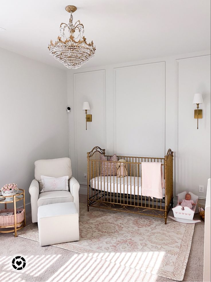 a baby's room with a chair, crib and chandelier