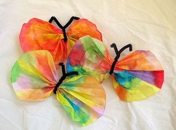 three colorful paper butterflies on a white sheet