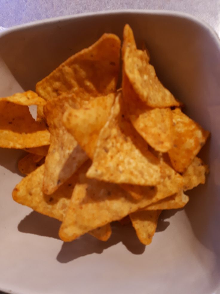 a white bowl filled with chips on top of a table