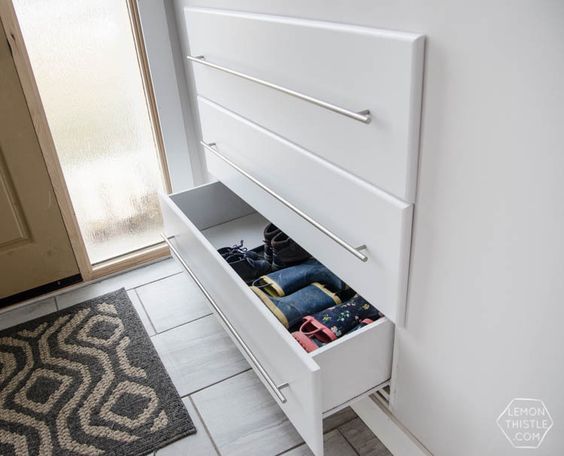 an open drawer on the side of a white cabinet in a room next to a door