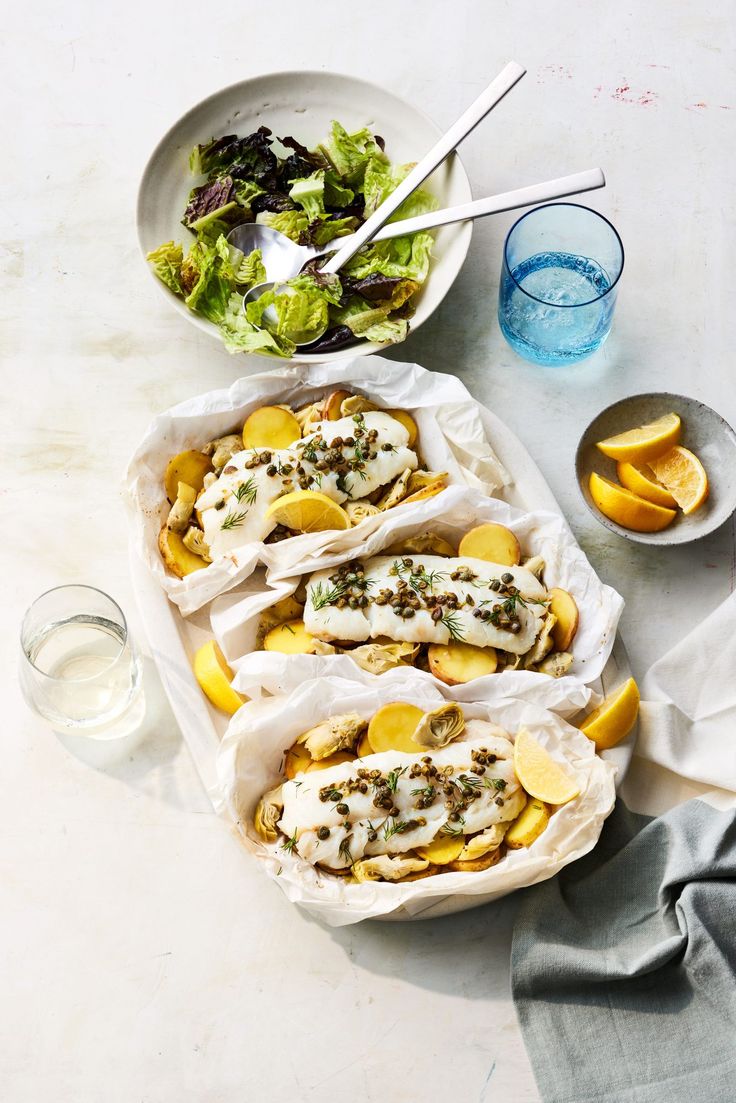 some tacos are sitting on a table next to a bowl of salad and water