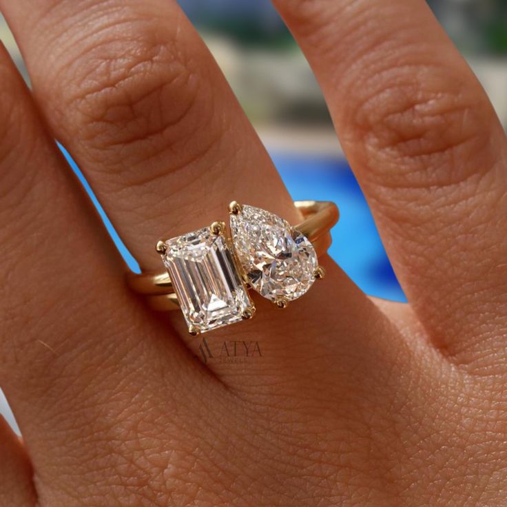 a woman's hand with two engagement rings on top of her finger, and the ring