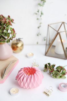 a table topped with pink vases filled with flowers next to candles and other items