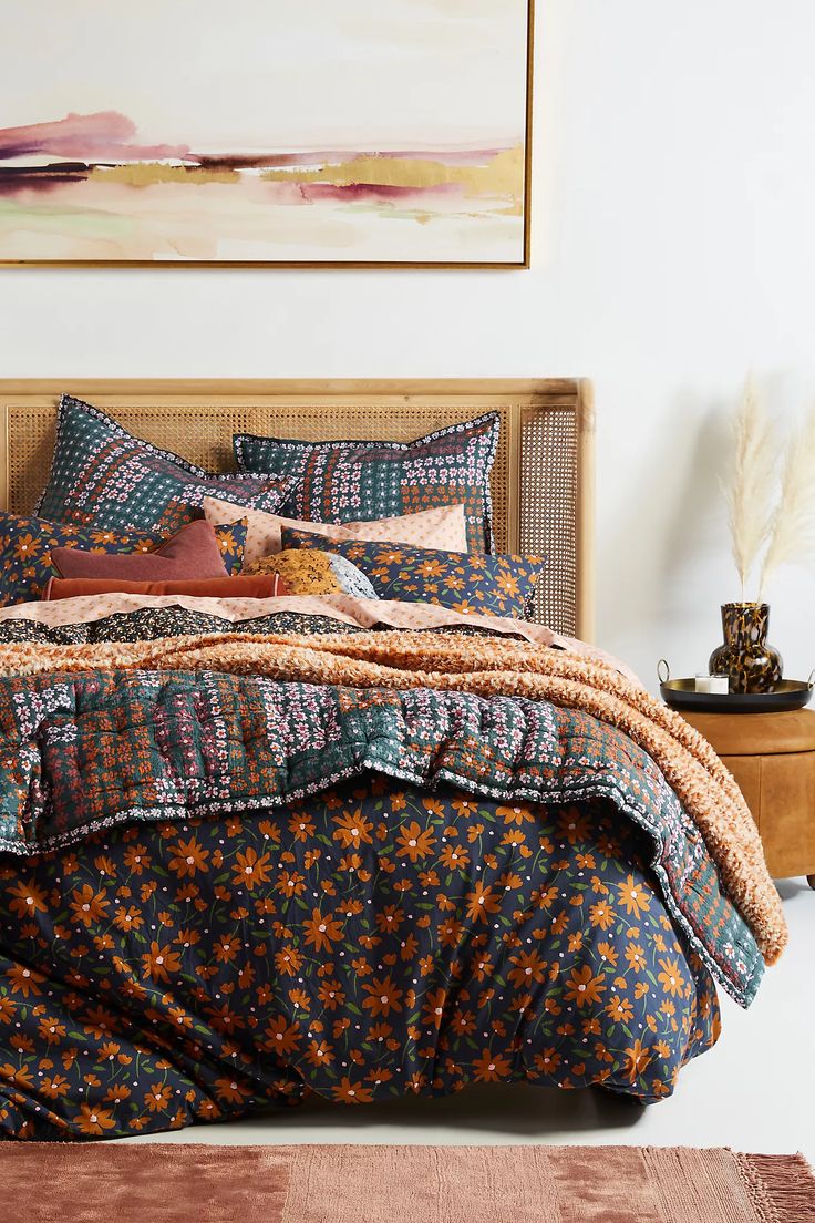 a bedroom with a bed covered in colorful comforter and pillows on top of it