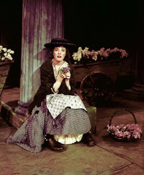 a woman is sitting on the ground with flowers in her hand and holding a flower