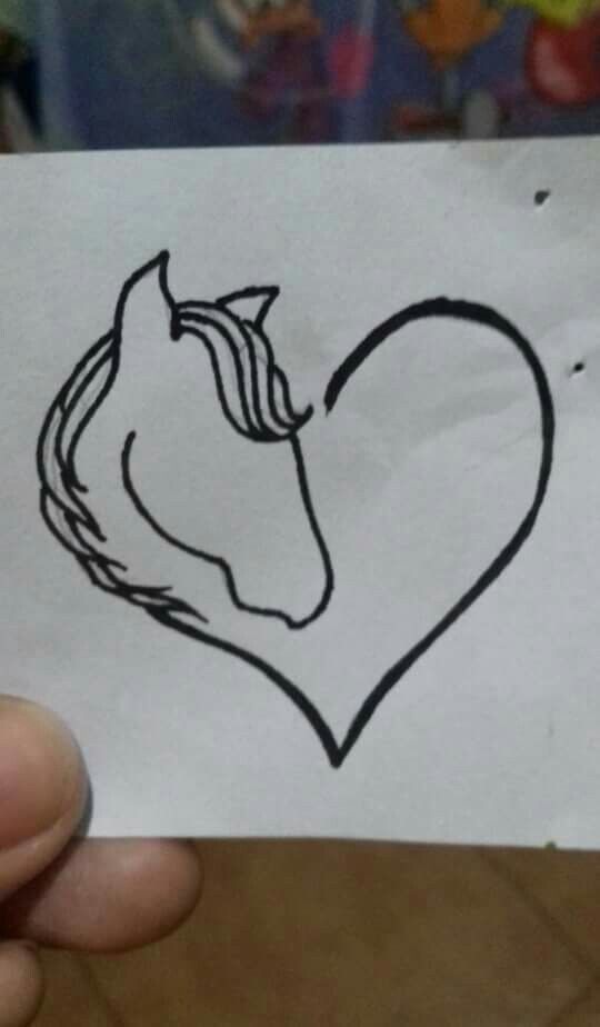 someone holding up a piece of paper with a drawing of a horse's head