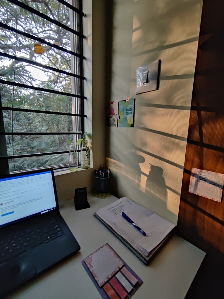 an open laptop computer sitting on top of a desk next to a notebook and pen