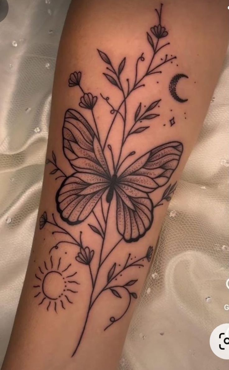 a black and white photo of a butterfly with flowers on it's arm, next to the moon