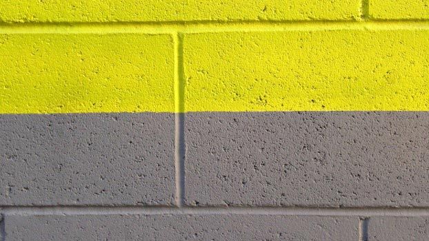 a red fire hydrant sitting next to a yellow and gray brick wall on the side of a building