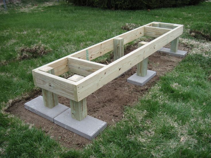 two wooden benches sitting on top of cement blocks in the middle of some grass and dirt