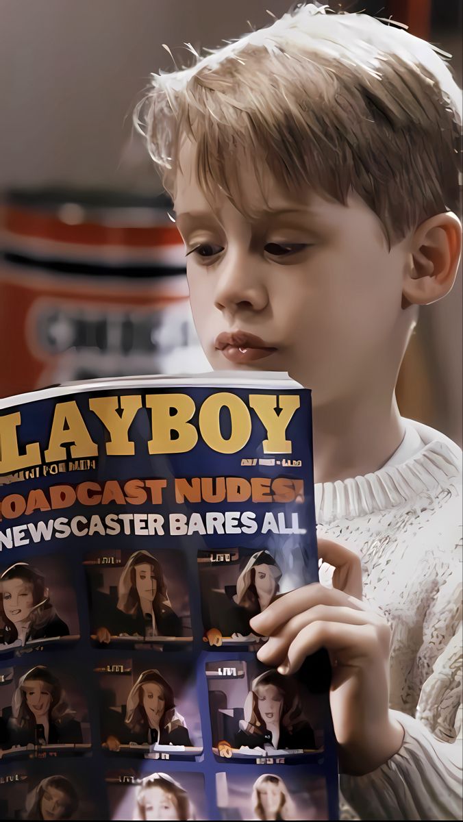 a young boy is reading a newspaper and looking at the pages with newscast babes all over it