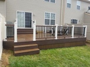 a deck with steps and railings in front of a house