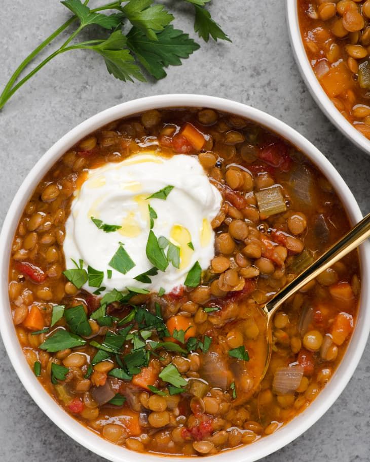 two white bowls filled with beans and sour cream, garnished with parsley