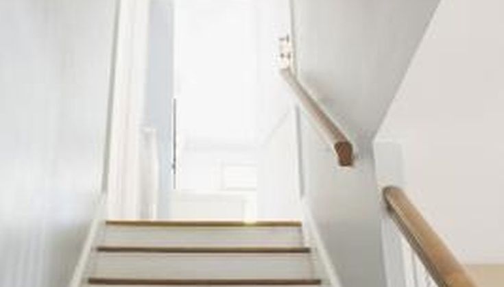 an empty staircase with white walls and wood handrails