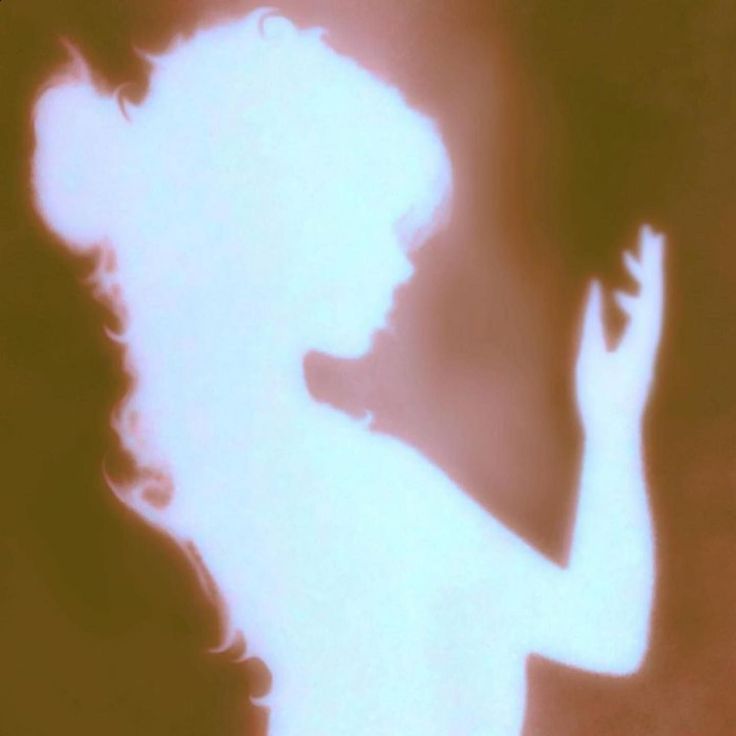 the silhouette of a woman holding a cell phone up to her ear and looking down