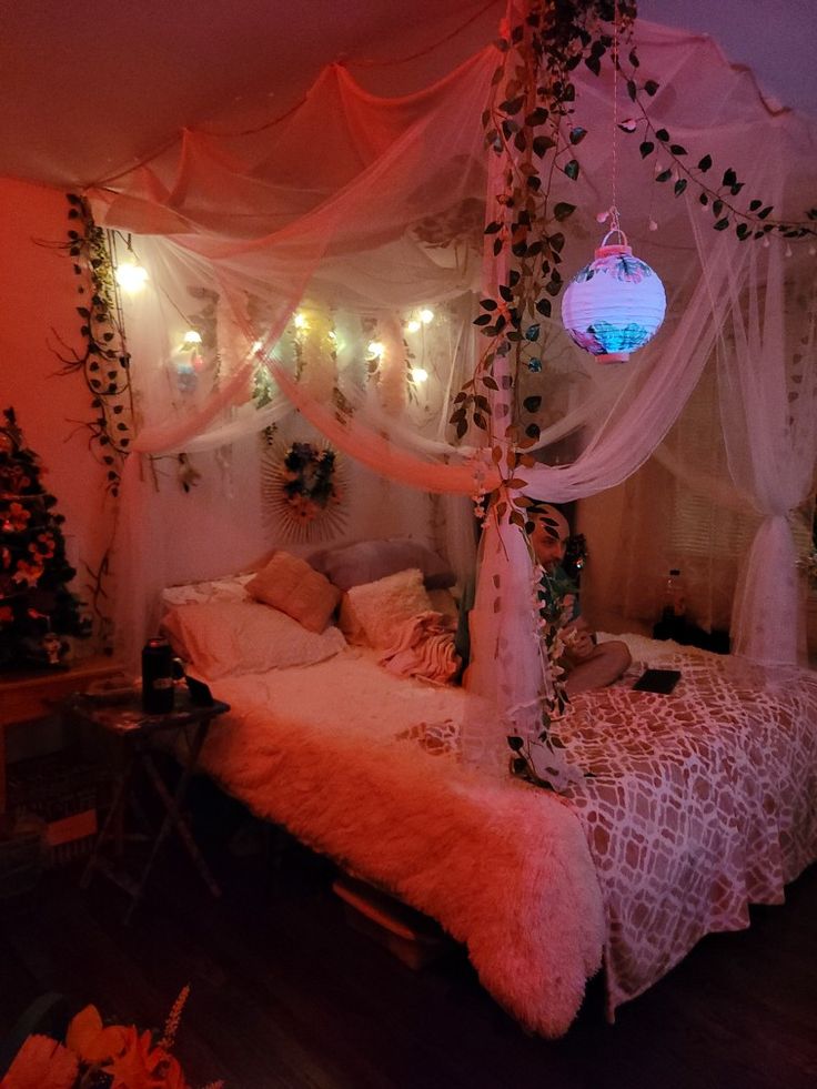 a canopy bed with white curtains and lights on the wall above it in a bedroom