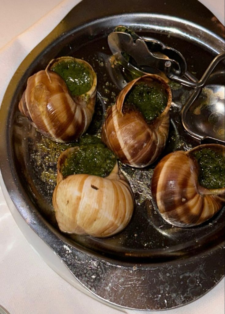 snails are being cooked in a pan with pesto