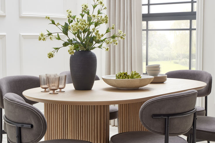 a dining room table with chairs and a bowl of flowers on the table next to it