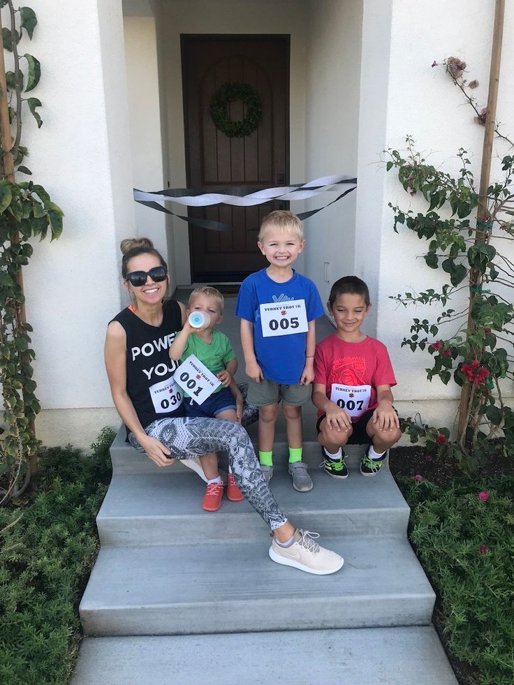 three children and one adult are posing on the steps in front of a house for a race