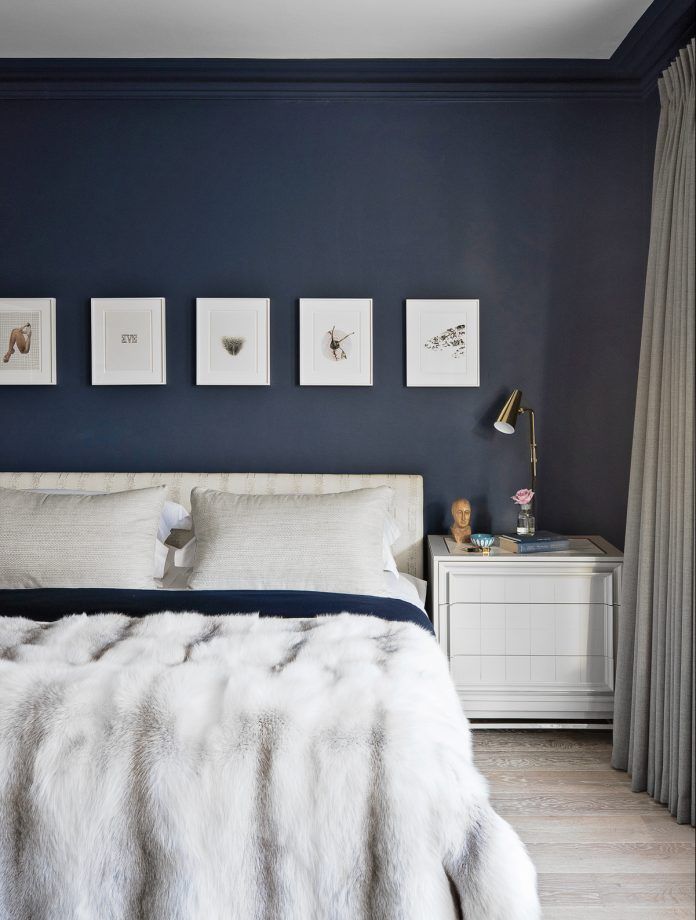 a bedroom with dark blue walls and white furniture, including a bed covered in fur