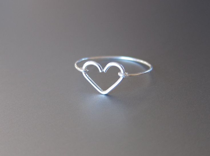 a heart shaped ring sitting on top of a gray surface with the word love written in it