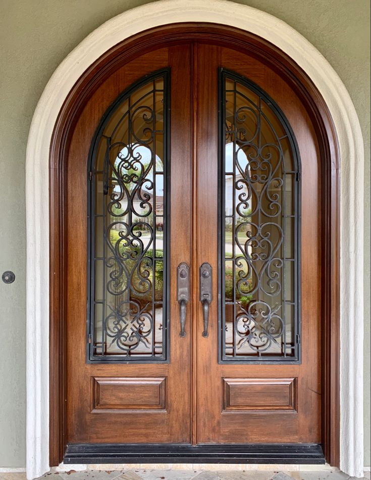 a pair of double doors with wrought iron work on the top and bottom panels above them