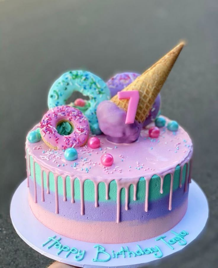 a birthday cake decorated with donuts, sprinkles and an ice cream cone