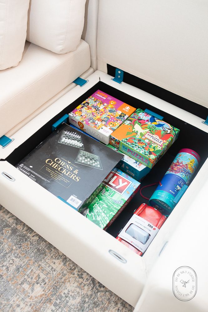 a white couch with some books and drinks in the drawer on it's side