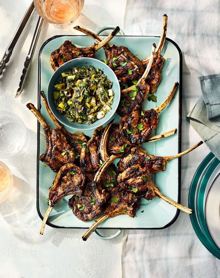 a platter with skewered lamb chops and a bowl of salsa