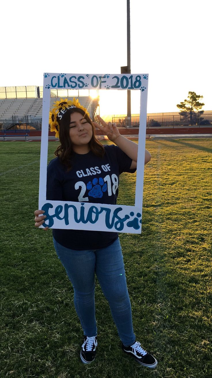 a woman holding up a sign that says class of 2016 in front of her face