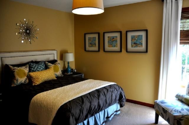 a bedroom with yellow walls and pictures on the wall