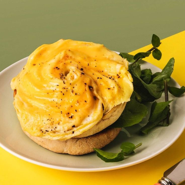 an omelet is sitting on top of a plate with greens and a knife