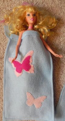 a barbie doll laying on the floor in a blue dress with pink butterflies and wings