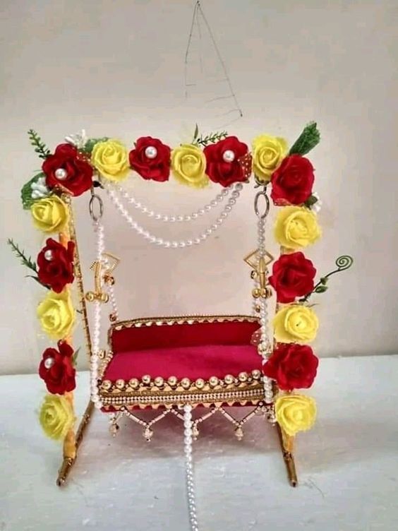 a red and yellow chair with flowers on the back is sitting in front of a white wall