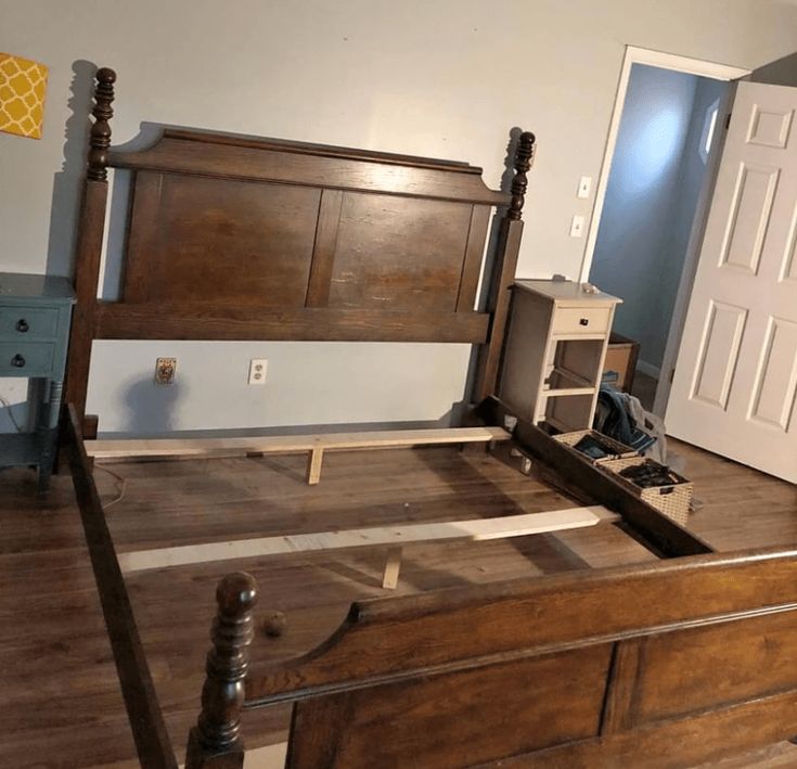 a bed with wooden headboard and foot board in a room that is being remodeled