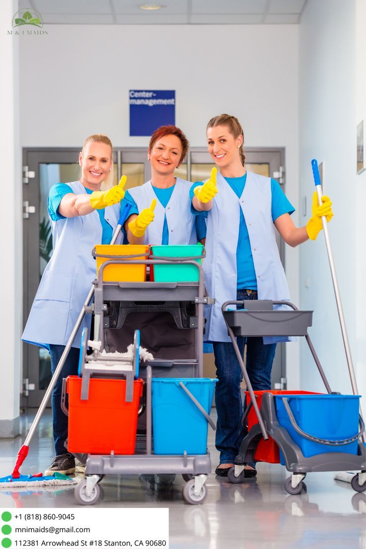 three women in scrubs are cleaning the floor with mop buckets and brooms