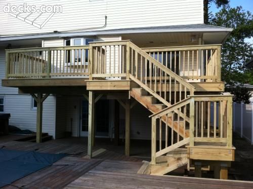 a wooden deck with stairs leading up to the upper floor and second story above it