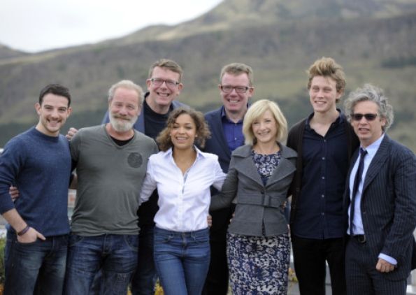 a group of people standing next to each other in front of a mountain with a sky background